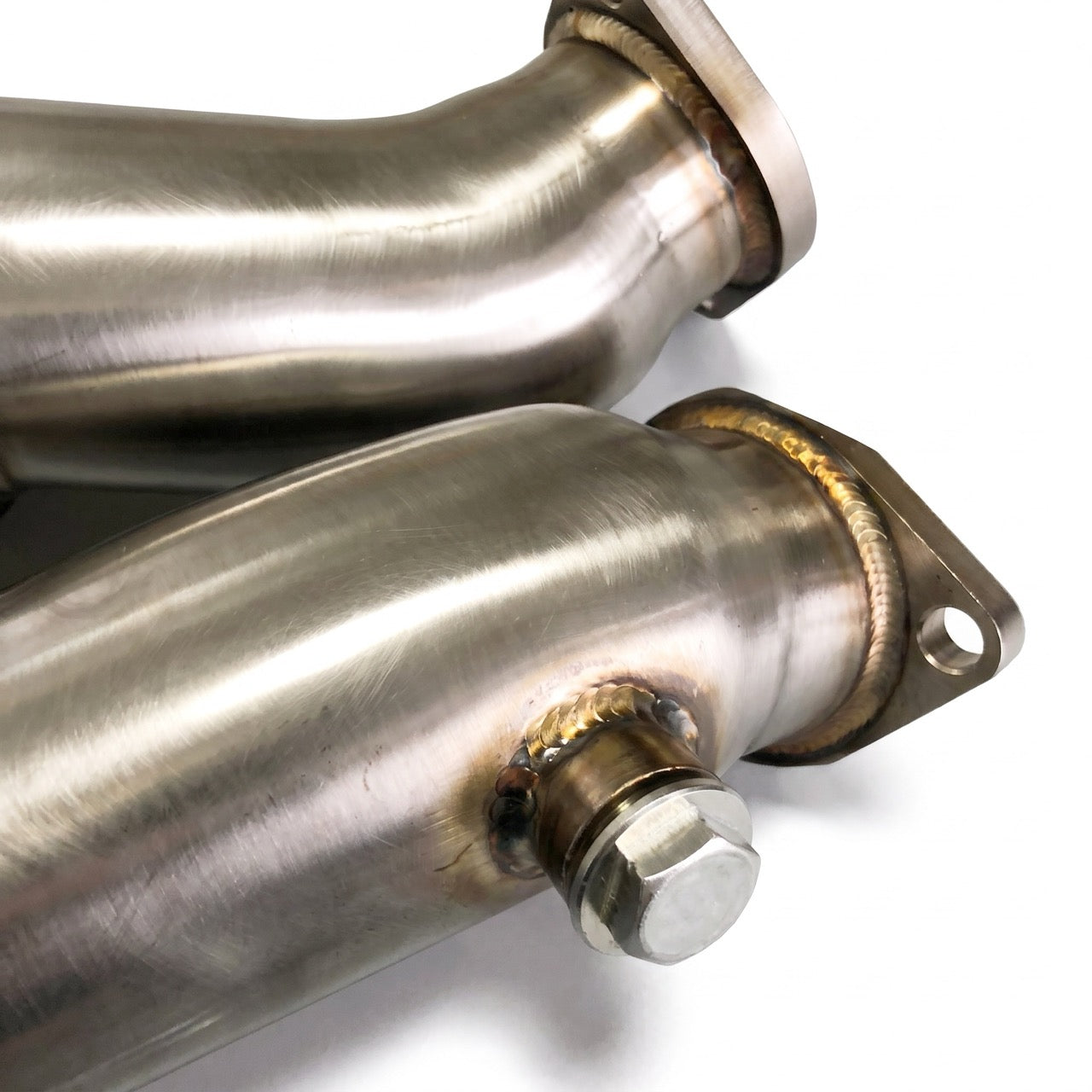 Close-up of stainless steel exhaust pipes with visible welds and bolted flanges on a white background.